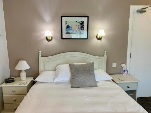 Un dormitorio con una cama blanca con una almohada gris encima. en Canterbury House, en Sidmouth
