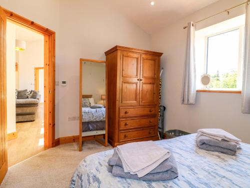 a bedroom with a bed and a dresser and a mirror at Teal Cottage in Melton Mowbray