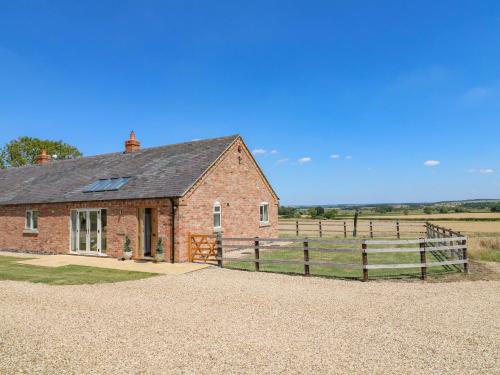 a brick house with a fence and a field at Teal Cottage in Melton Mowbray