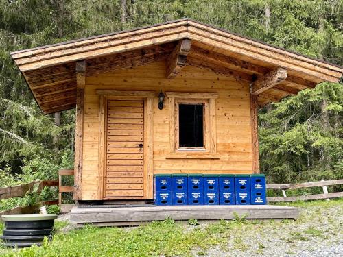 a small cabin with blue barrels in the grass at Wasserfallhütte Saalbach in Saalbach Hinterglemm