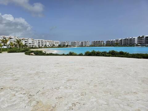 a sandy beach with buildings in the background and a large body of water at SantoriniRD in Punta Cana