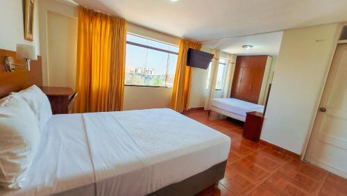 a bedroom with a white bed and a window at Manta Hotel Tacna in Tacna