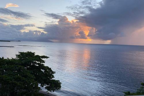 a sunset over the ocean with a tree in the foreground at Blue Horizon - Le Luxury Matavai Beach - Piscine - Vue Mer in Arue