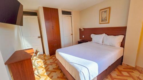 a bedroom with a white bed in a room at Manta Hotel Tacna in Tacna