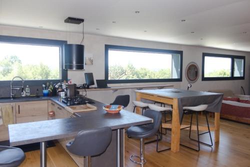 Il comprend une cuisine avec une table et des chaises ainsi que 2 fenêtres. dans l'établissement Gîte écologique avec vue Forêt & Vallée Dordogne !, à Bétaille