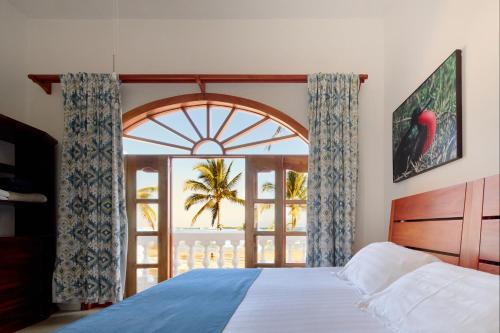 a bedroom with a bed and a large window at Hotel Albemarle Galapagos Beachfront in Puerto Villamil