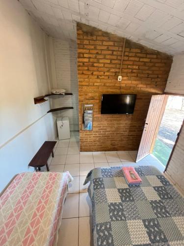 a bedroom with a bed and a flat screen tv at Quintal De Minas in Delfinópolis