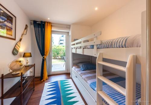 una camera da letto con due letti a castello e una finestra di Saint Raphael appartement 4 étoiles neuf en rez de jardin privatif a Saint-Raphaël