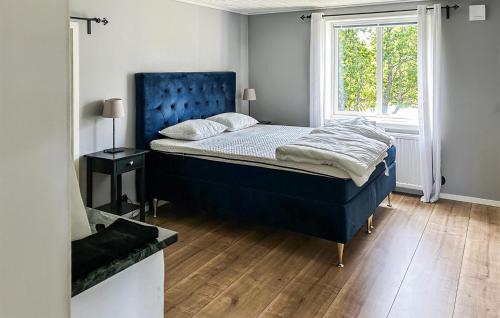 a bedroom with a bed with a blue headboard and a window at Cozy Home In Dörarp With Sauna in Dörarp