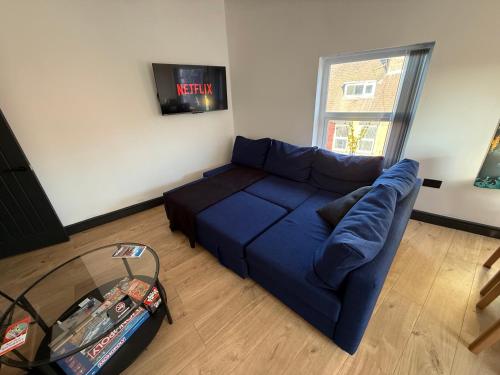 a blue couch in a living room with a window at The Anfield Loft in Liverpool