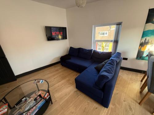 a living room with a blue couch and a window at The Anfield Loft in Liverpool