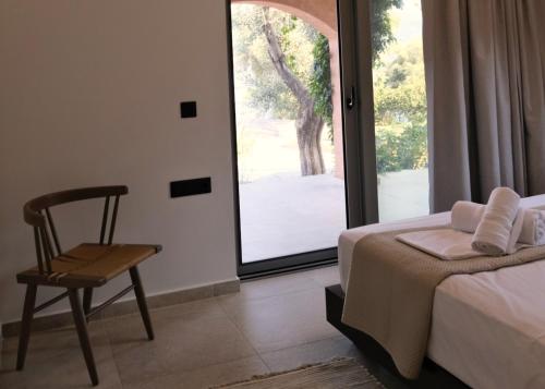 a bedroom with a bed and a chair and a window at Trabala Ionian Living in Paleros