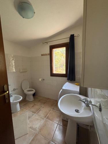 a bathroom with a sink and a toilet and a window at Agrustos Paradise in Budoni