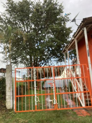 an orange gate in front of a house with a tree at Hostal Las Hamacas , Entre Montañas y Luces in Villamaría