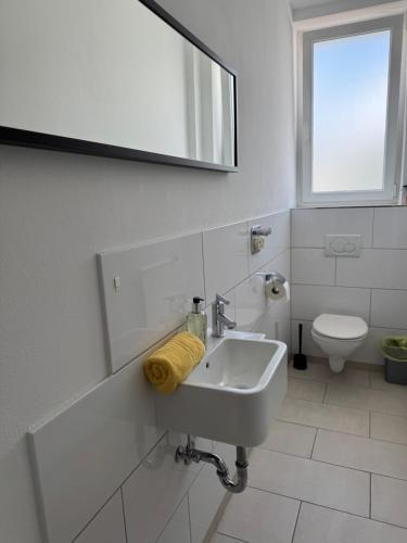 a white bathroom with a sink and a toilet at Pension Albert - Monteurzimmer in Stuttgart
