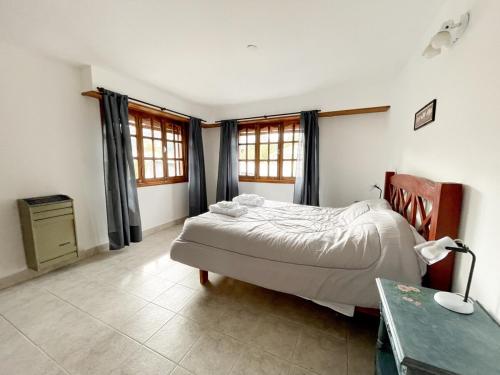a bedroom with a bed and a desk and windows at Hermoso departamento en Esquel, amplio y luminoso in Esquel