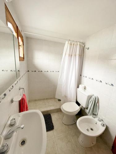 a white bathroom with a toilet and a sink at Hermoso departamento en Esquel, amplio y luminoso in Esquel
