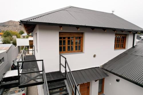 a white house with a black roof and stairs at Hermoso departamento en Esquel, amplio y luminoso in Esquel