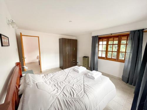 a bedroom with a large white bed and a window at Hermoso departamento en Esquel, amplio y luminoso in Esquel