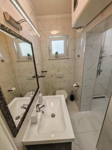 ein weißes Badezimmer mit Waschbecken und Spiegel in der Unterkunft Villa Infinity in Krk