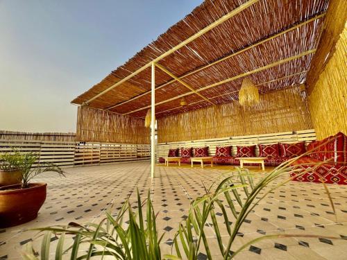a large building with benches and a straw roof at SurfsHub Hostel Tamraght in Tamraght Ouzdar
