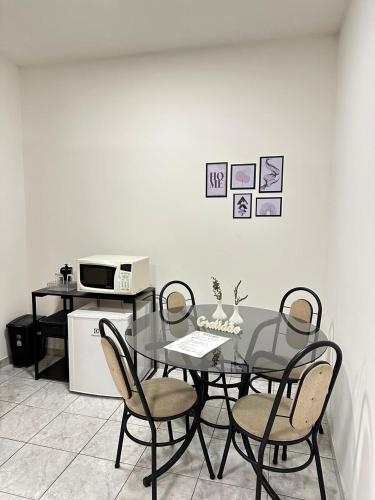 a dining room table with four chairs and a microwave at Suíte Central in Nova Friburgo