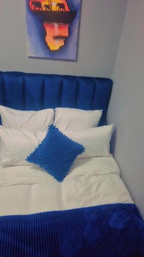 a bed with a blue headboard and white pillows at Royal Blue Family Haven in Rustenburg