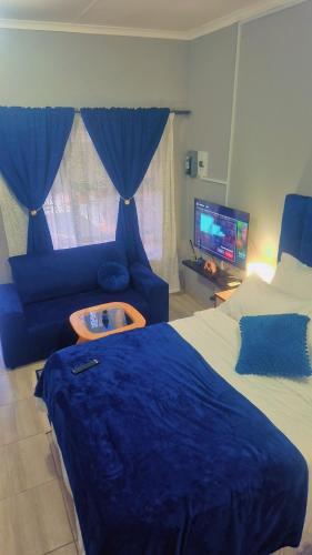 a bedroom with a blue bed and a blue couch at Royal Blue Family Haven in Rustenburg