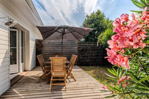 un patio avec une table, des chaises et un parasol dans l'établissement Pretty wooden house with terrace - Bassin d'Arcachon, à Arès