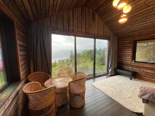 a room with chairs and a table and a large window at Forest Hideaway With Scenic View in Fiskå
