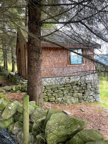 a stone building with a window and a tree at Forest Hideaway With Scenic View in Fiskå