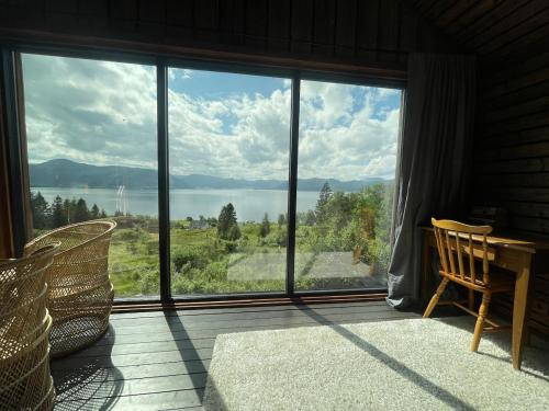 a room with a large window with a view of the water at Forest Hideaway With Scenic View in Fiskå