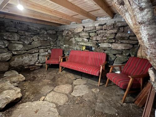 two red chairs and a table in a stone room at Forest Hideaway With Scenic View in Fiskå