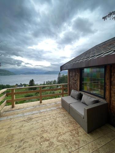 a couch on a deck with a view of the water at Forest Hideaway With Scenic View in Fiskå