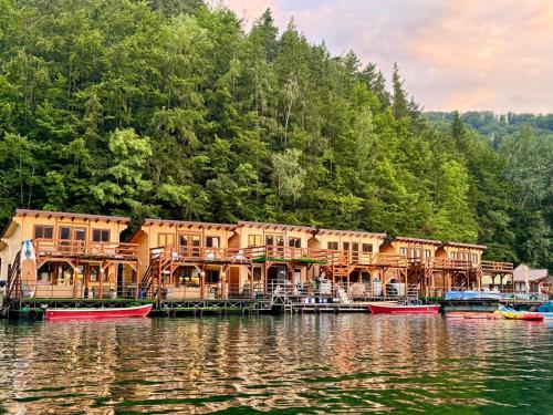 a house on a lake with boats in the water at Holiday Bicaz Bungalows On The Lake in Bicaz