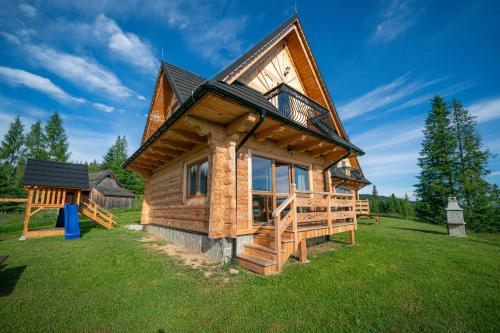 a log cabin with a large deck on a grass field at Niedźwiedź nad Chochołowską in Witów