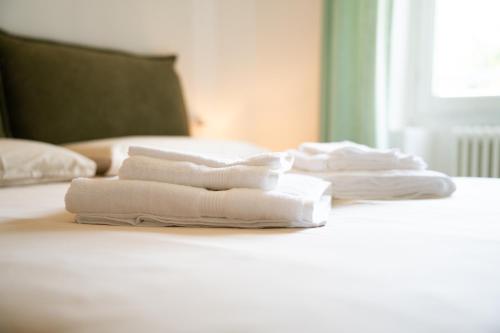 four white towels are stacked on a bed at I Madòna in Dongo