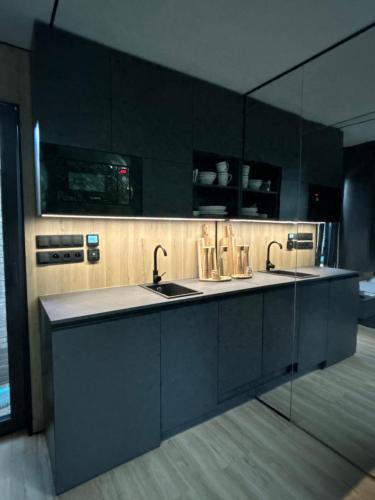 a black kitchen with two sinks and a mirror at Spiegelhuisje aan zee in Burgh Haamstede