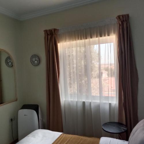 a bedroom with a bed and a window with curtains at MDE Loisir Tanjis m in Tangier