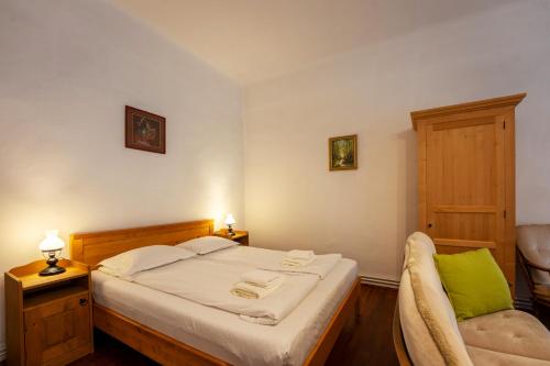 a small bedroom with a bed and a chair at Pensiunea Bastion - La Strada - in Sighişoara