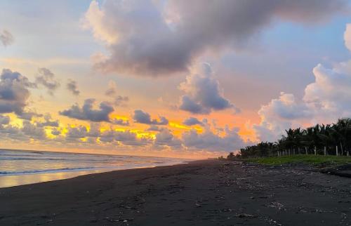 a beach with a cloudy sky and the ocean at The sunrises are lovely, and the privacy is exceptional in Sipacate