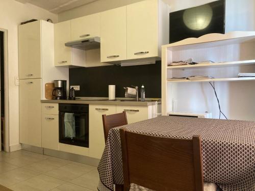 une cuisine avec des armoires blanches et une table avec des chaises dans l'établissement STRASBOURG PROCHE Petite France, à Strasbourg