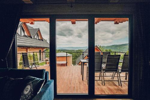 a view from a glass door of a deck with chairs at Osada Kanada in Istebna
