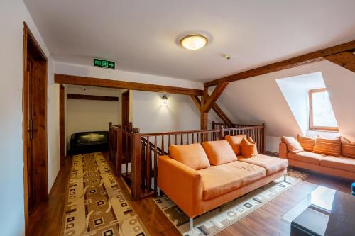 a living room with an orange couch and a window at Pensiunea Bastion - La Strada - in Sighişoara