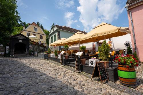a cobblestone street with tables and umbrellas at Pensiunea Bastion - La Strada - in Sighişoara