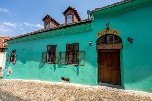 a bright green building with a wooden door at Pensiunea Bastion - La Strada - in Sighişoara