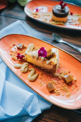 an orange plate with a piece of cake on a table at Tilajari Hotel Resort in Fortuna