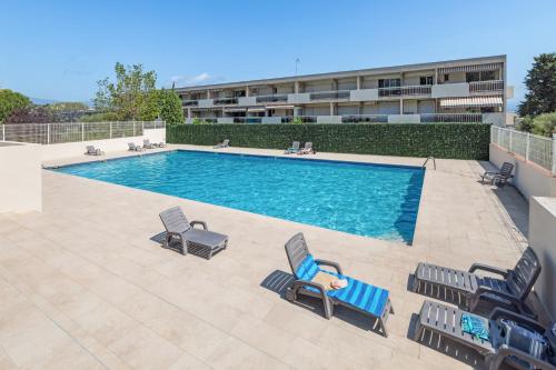 - une piscine avec 2 chaises longues et 2 chaises dans l'établissement Antibes PISCINE ET TENNIS, à Antibes