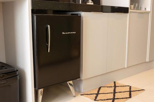 a black refrigerator in a kitchen with white cabinets at Alta Garden Housi João Pessoa by Carpediem in João Pessoa