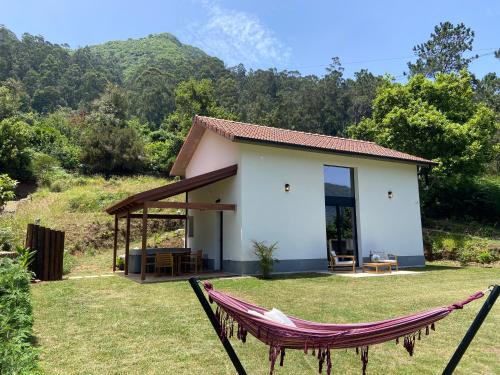 a small white house with a hammock in the yard at Casa Kalm - Private house with jacuzzi and mountain view in Senhora do Rosário
